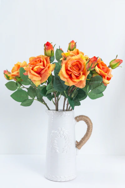 a bouquet of orange roses in a white vase