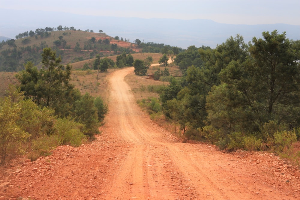 a dirt road surrounded by trees and hills