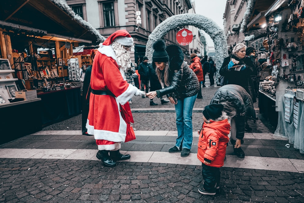 a man dressed as santa claus handing something to a child