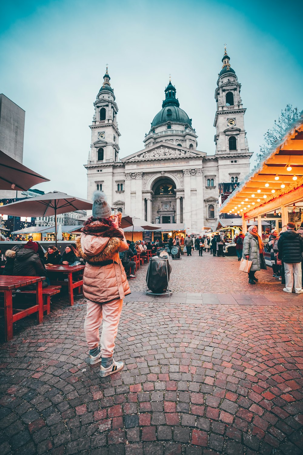 a woman walking down a cobblestone street in front of a building