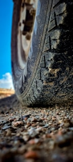 A close-up of a truck's wheel on a gravel road.