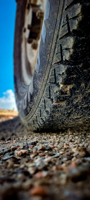 Close-up of rugged tires gripping rocky terrain, dust swirling in the sunlight.