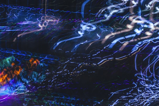 A swirling array of colorful lights creating abstract patterns, with blue, purple, and orange streaks flowing dynamically across a dark background.