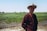 a man wearing a hat standing in a field