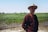 a man wearing a hat standing in a field