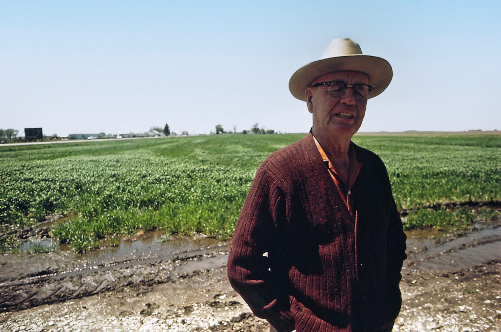 a man wearing a hat standing in a field