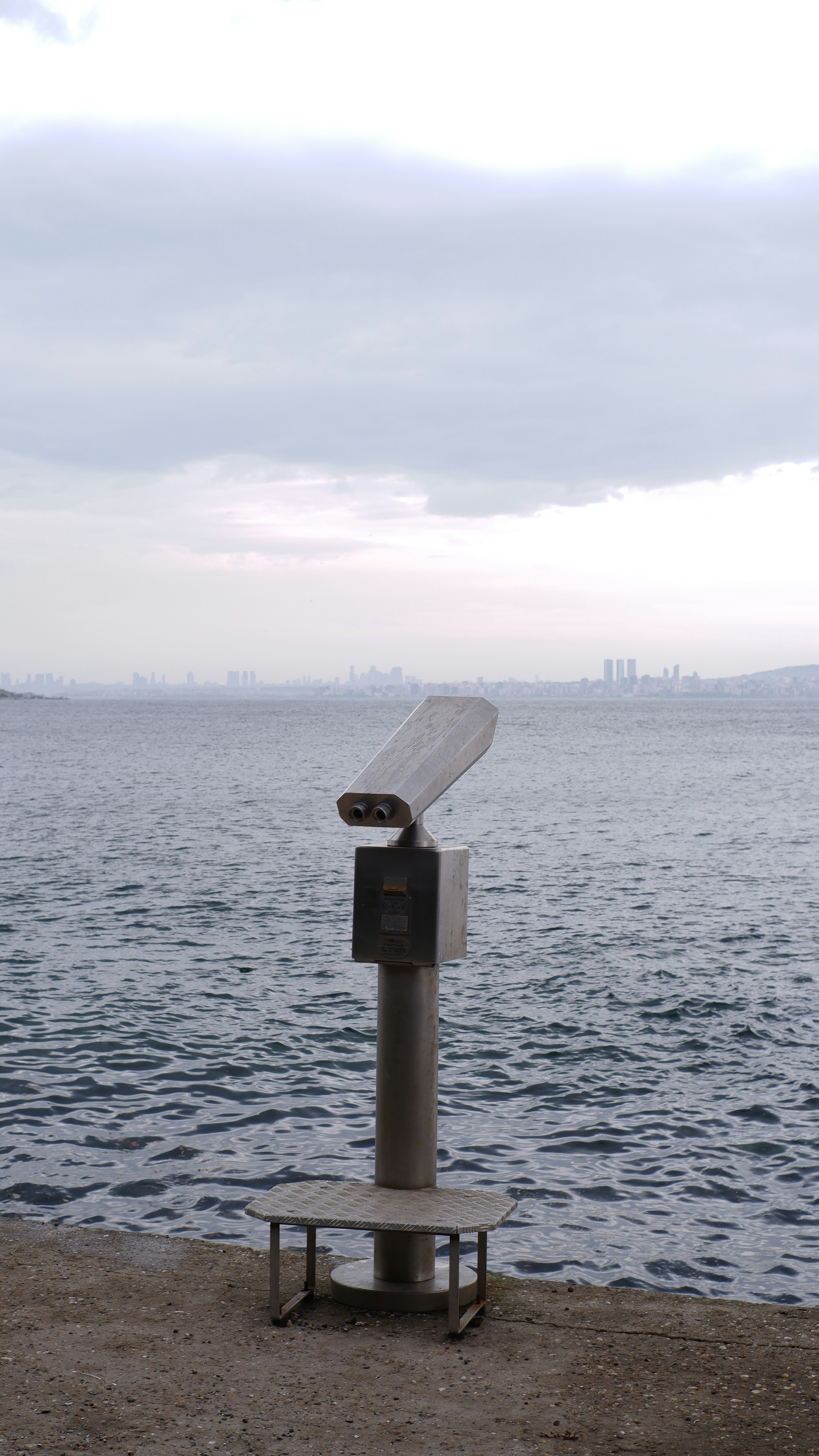 a metal object sitting on top of a beach next to a body of water