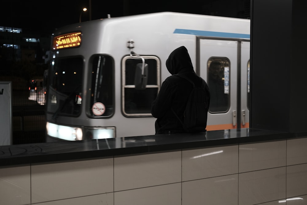 a person in a black hoodie stands at a counter in front of a subway