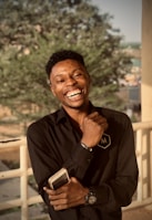 A tech blogger holding a smartphone, smiling while reviewing it.