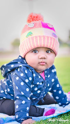 A baby bundled in a warm, colorful seasonal jacket with matching hat