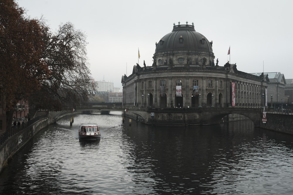 a boat traveling down a river next to a large building