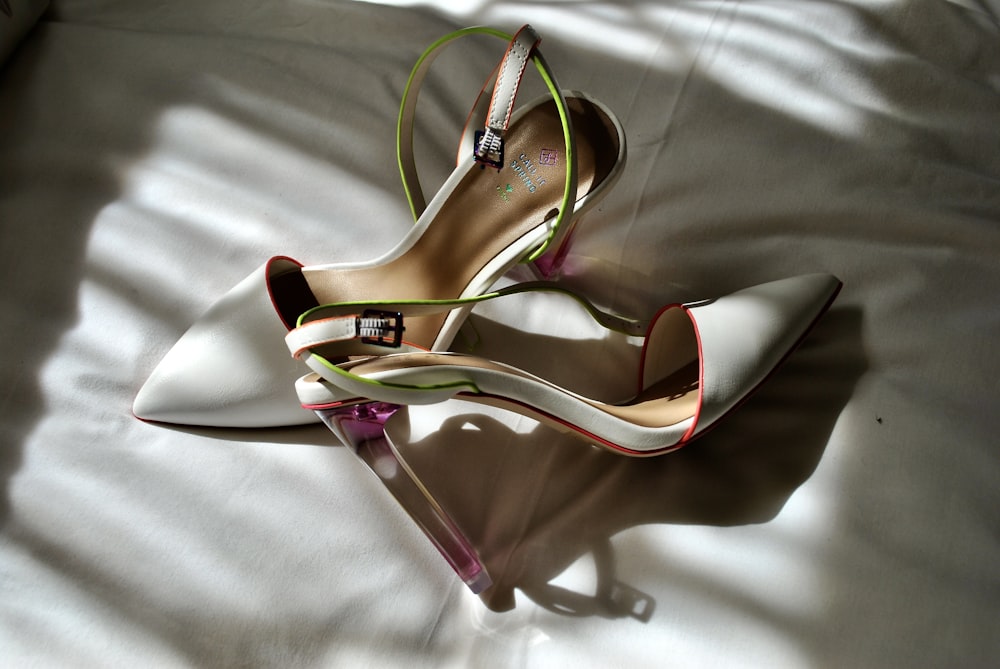 a pair of white high heel shoes on a bed