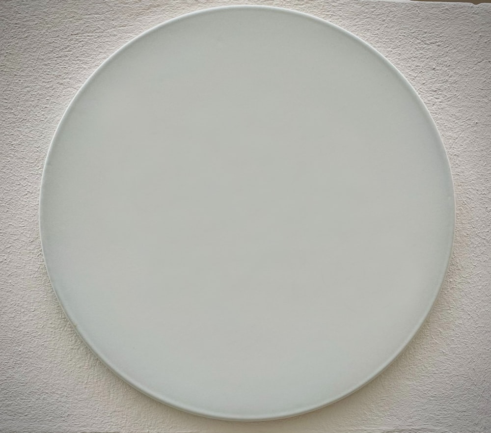 흰 벽 위에 놓인 하얀 접시