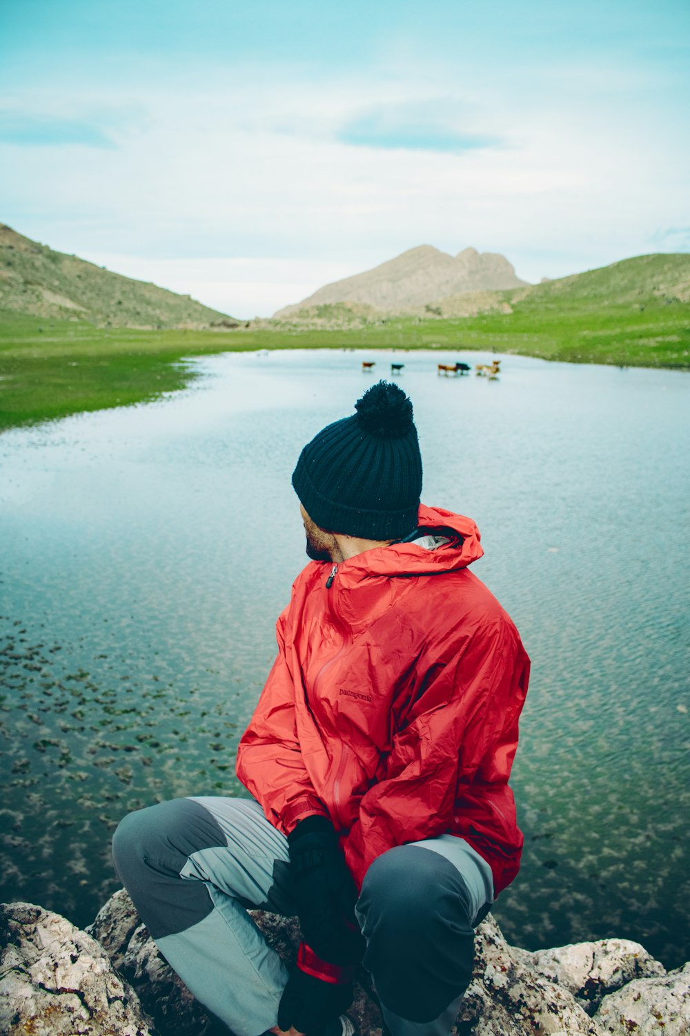 a person sitting on a rock near a body of water