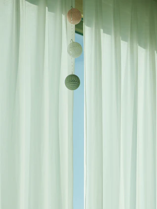 Minimalist tab top curtains gently flowing in a breezy window with monochrome pillow cases on a nearby sofa