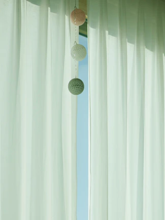 Minimalist living room with soft white curtains filtering natural light.