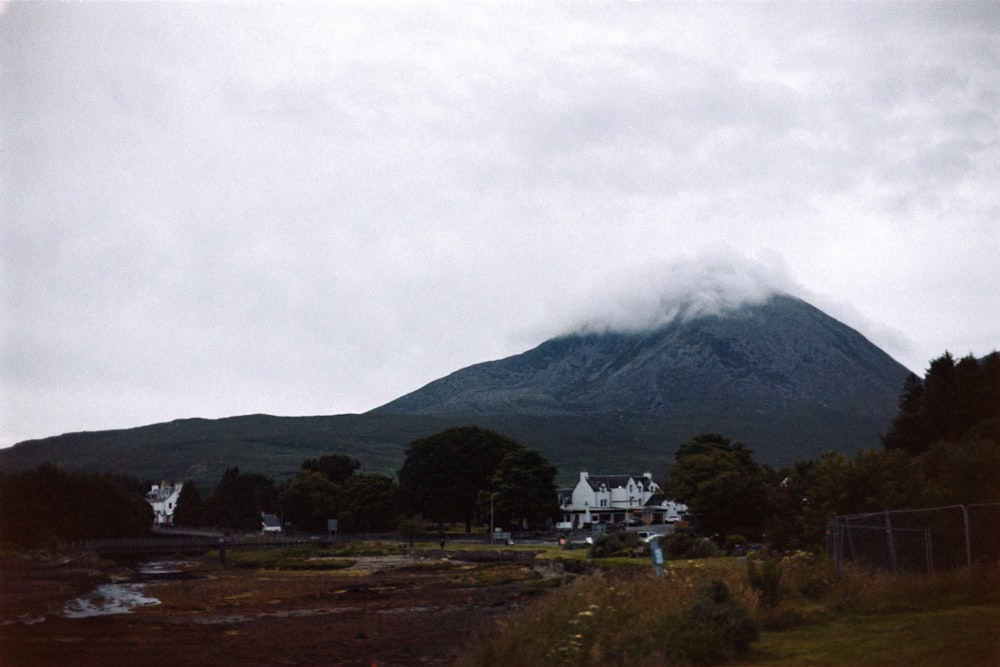 a large mountain in the distance with houses in the foreground