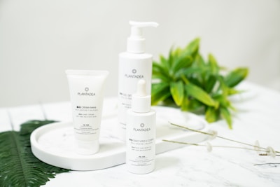 A trio of eloura skincare products arranged on a clean white surface with green leaves.