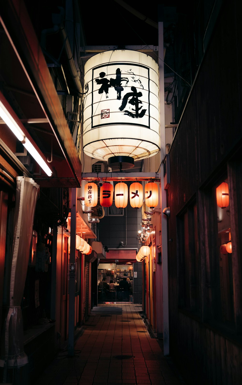 a narrow alley way with lanterns hanging from the ceiling