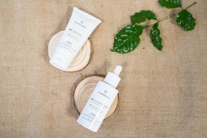 Hands applying natural skincare products on a wooden table