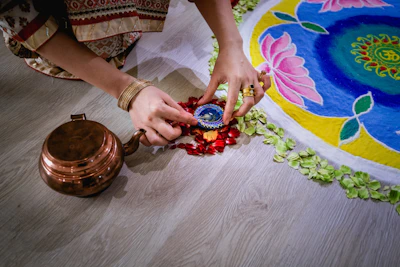 Handmade brass urli placed artistically at an entrance adorned with rangoli.