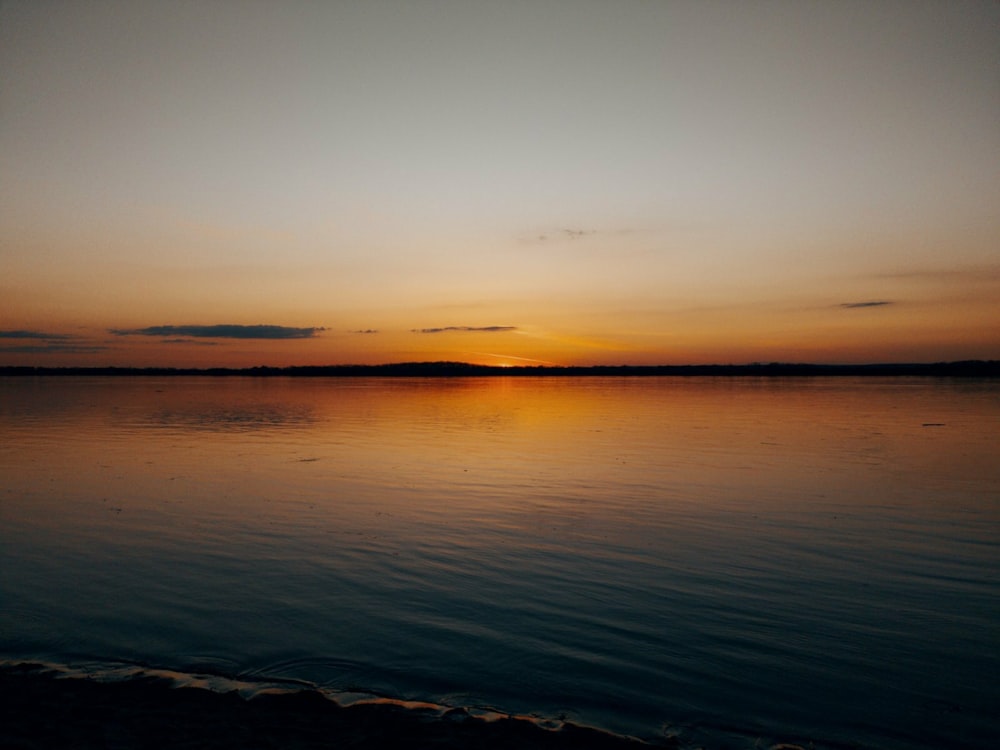 a body of water with a sunset in the background