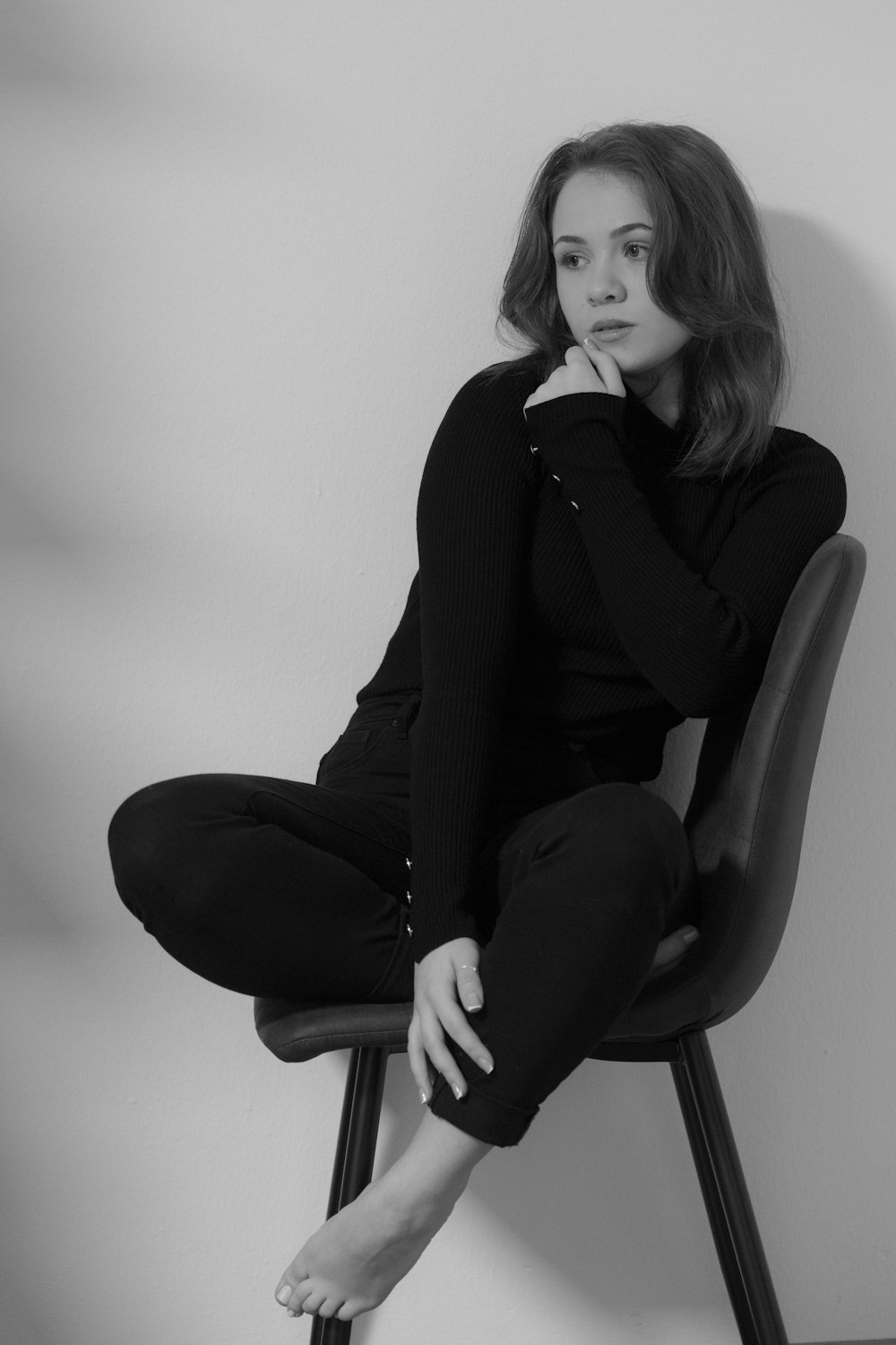 a woman sitting on a chair with her hand on her chin