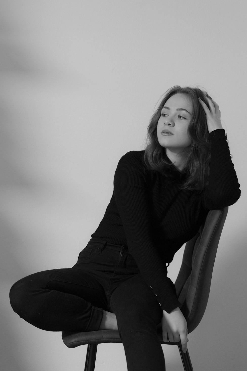 a woman sitting on a chair with her hand on her head