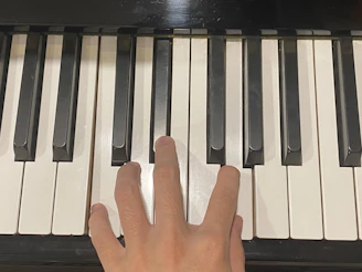 Close-up of hands playing piano keys with colorful soundwaves surrounding.