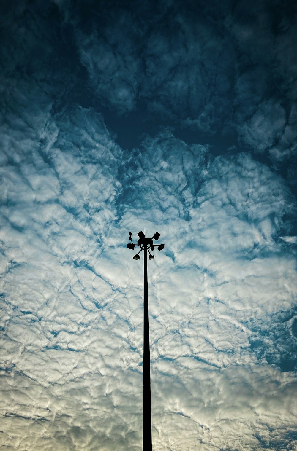 a tall pole sitting under a cloudy blue sky