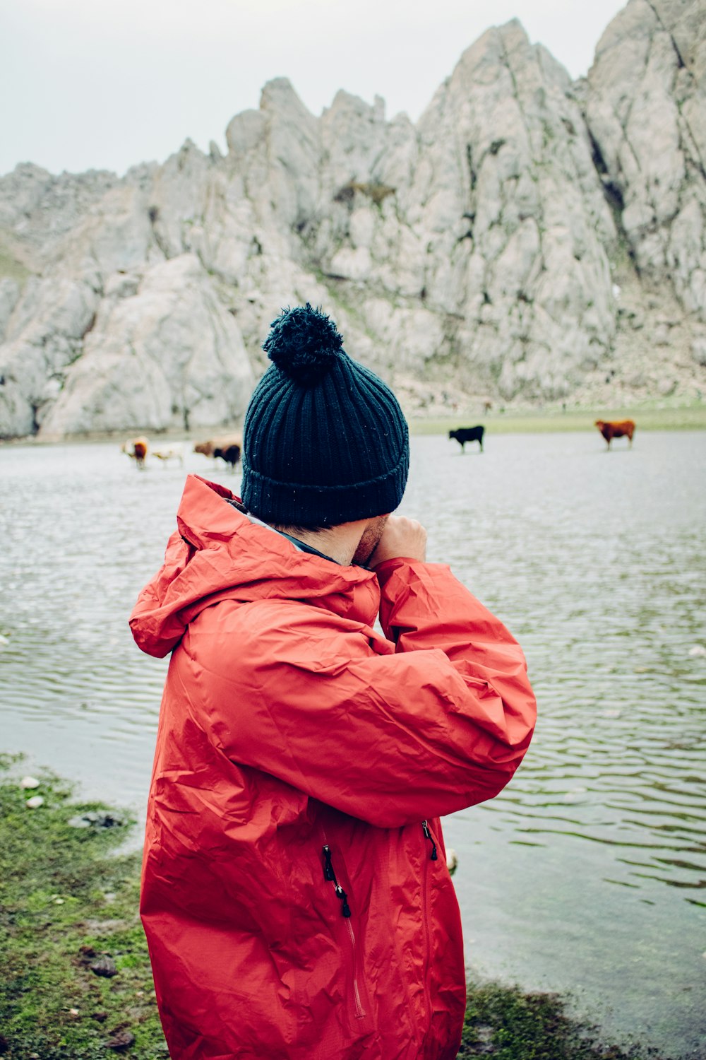 a person in a red jacket standing by a lake