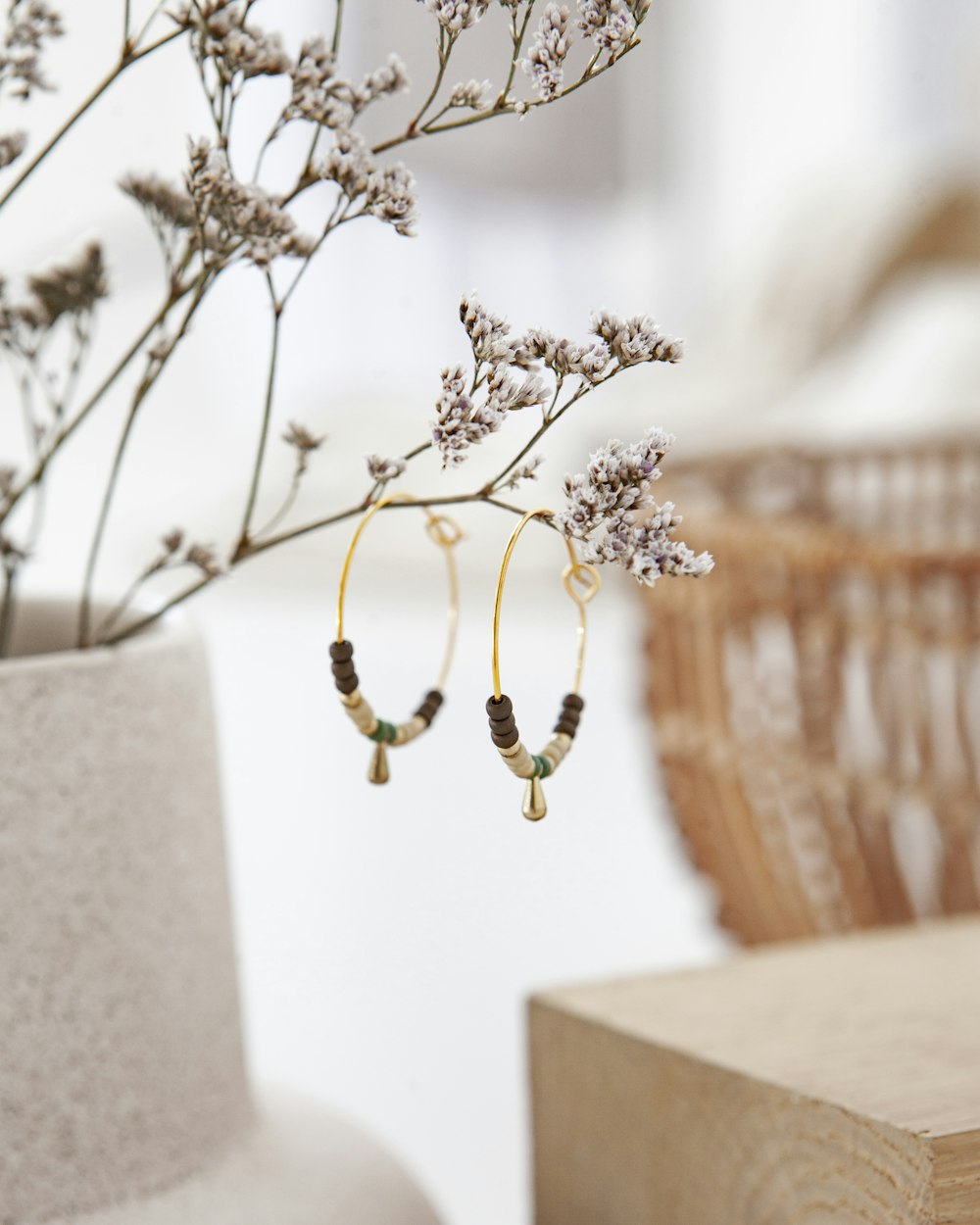 a pair of earrings hanging from a branch of a plant