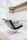 A modern chair with a sleek, angular design sits in an elegant, well-lit interior space with high ceilings and a large skylight. The chair features a combination of leather and metal elements, exuding a minimalist and sophisticated aesthetic.