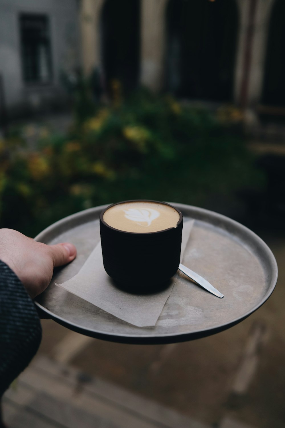 a person holding a tray with a cup of coffee on it