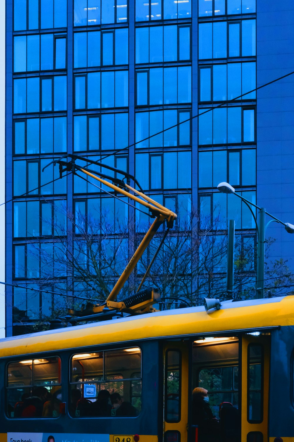 a yellow and blue bus parked in front of a tall building