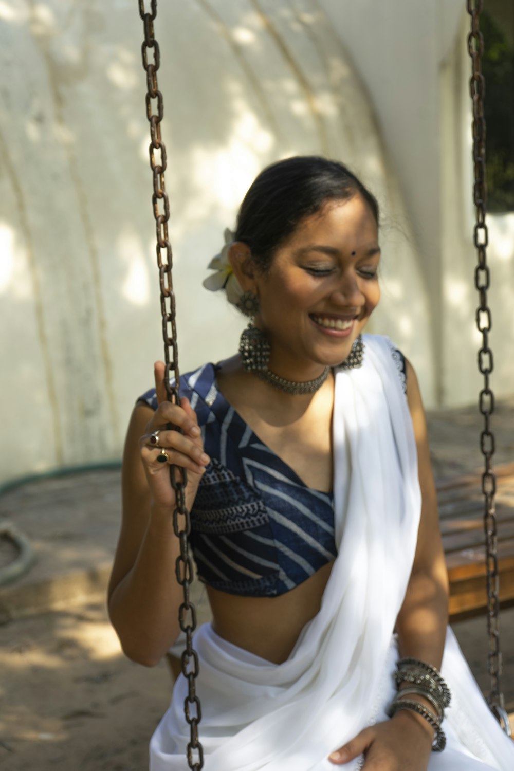 a woman in a white sari sitting on a swing