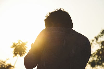 a man standing in front of the sun with his back to the camera