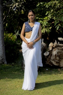 A woman gracefully draped in a colorful saree standing in a serene outdoor setting