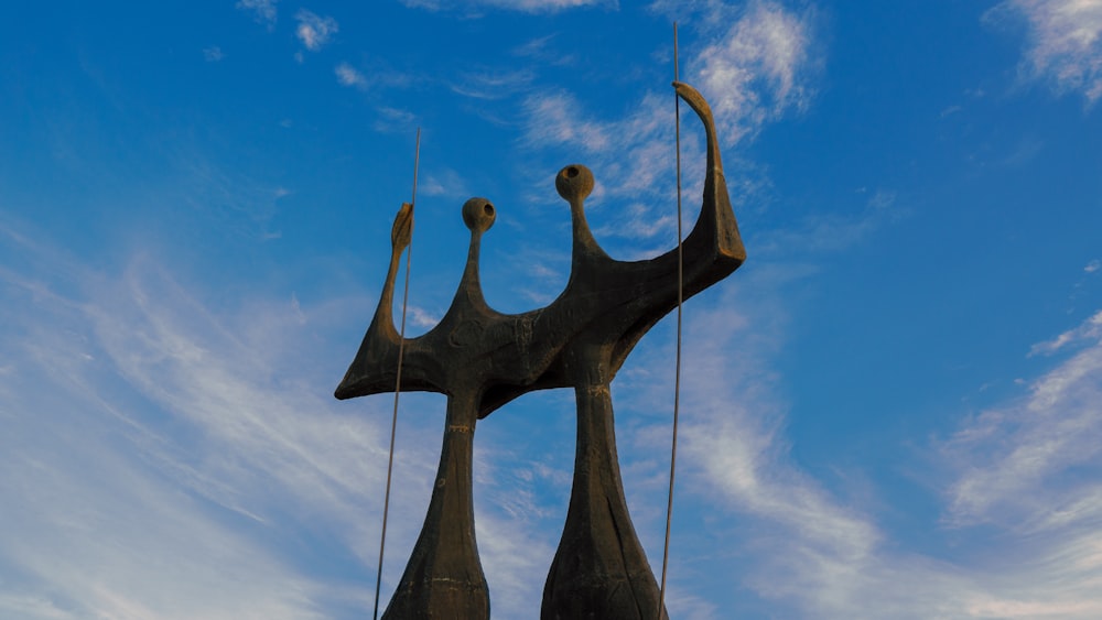 a statue of two people holding hands with a sky background