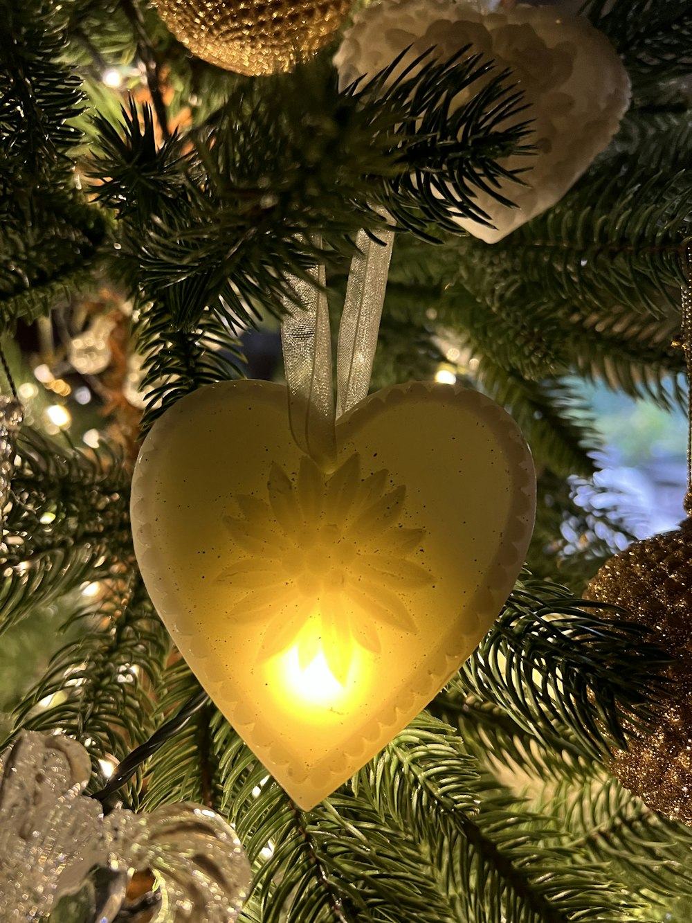 a heart shaped ornament hanging from a christmas tree