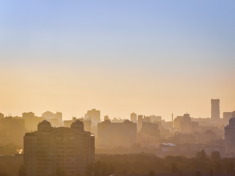 A global city skyline at sunrise, highlighting iconic financial buildings bathed in soft red light.