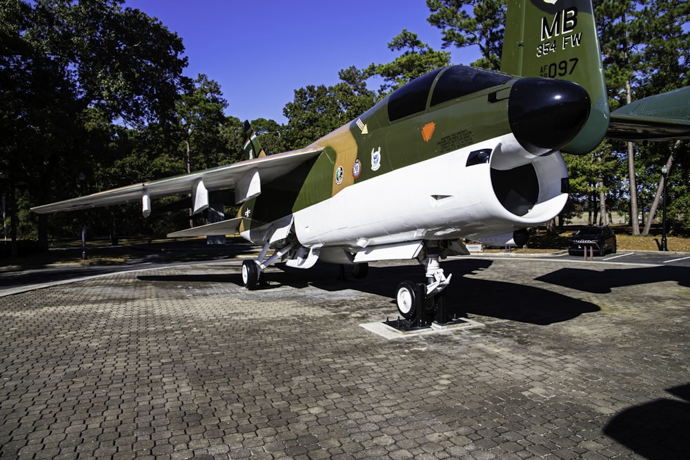 a green and white fighter jet sitting on top of a parking lot