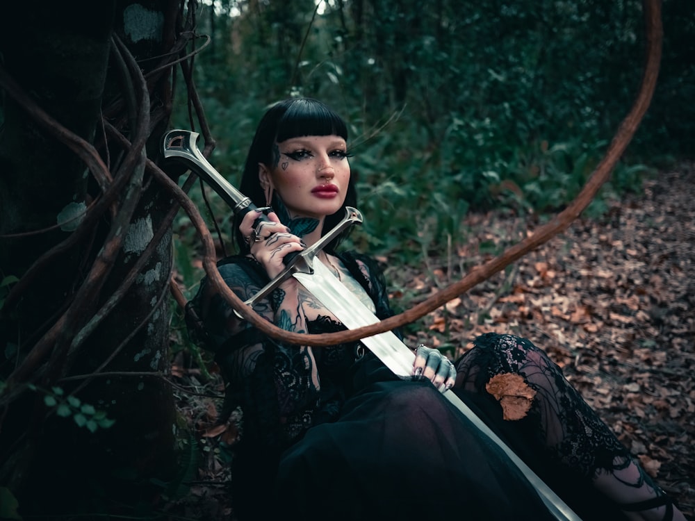 a woman sitting on the ground holding a sword