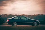 Family stepping out of a sleek car, smiling softly against a charcoal sky.