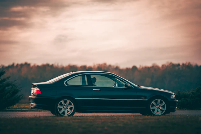 Family stepping out of a sleek car, smiling softly against a charcoal sky.