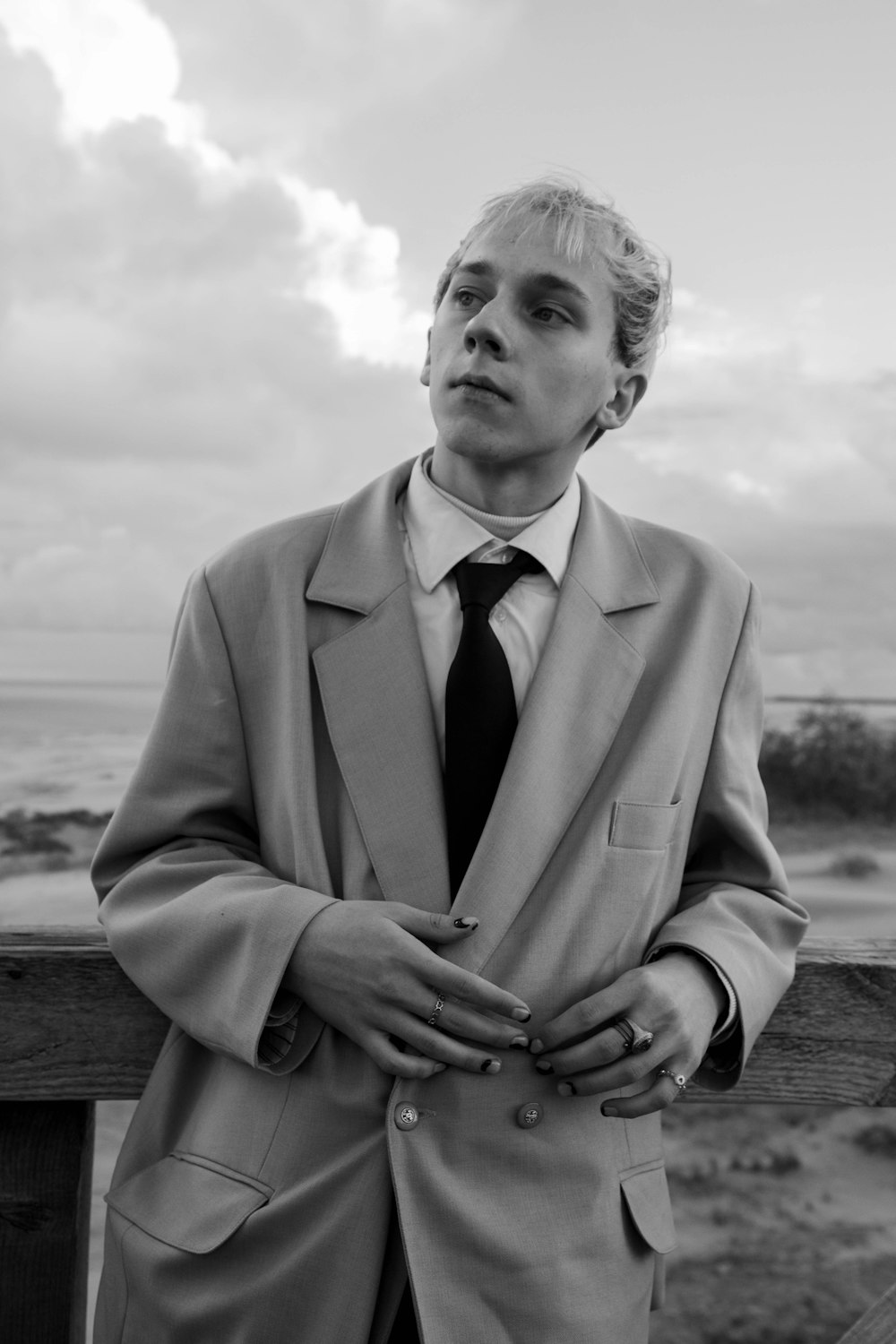 a man in a suit and tie standing by a fence