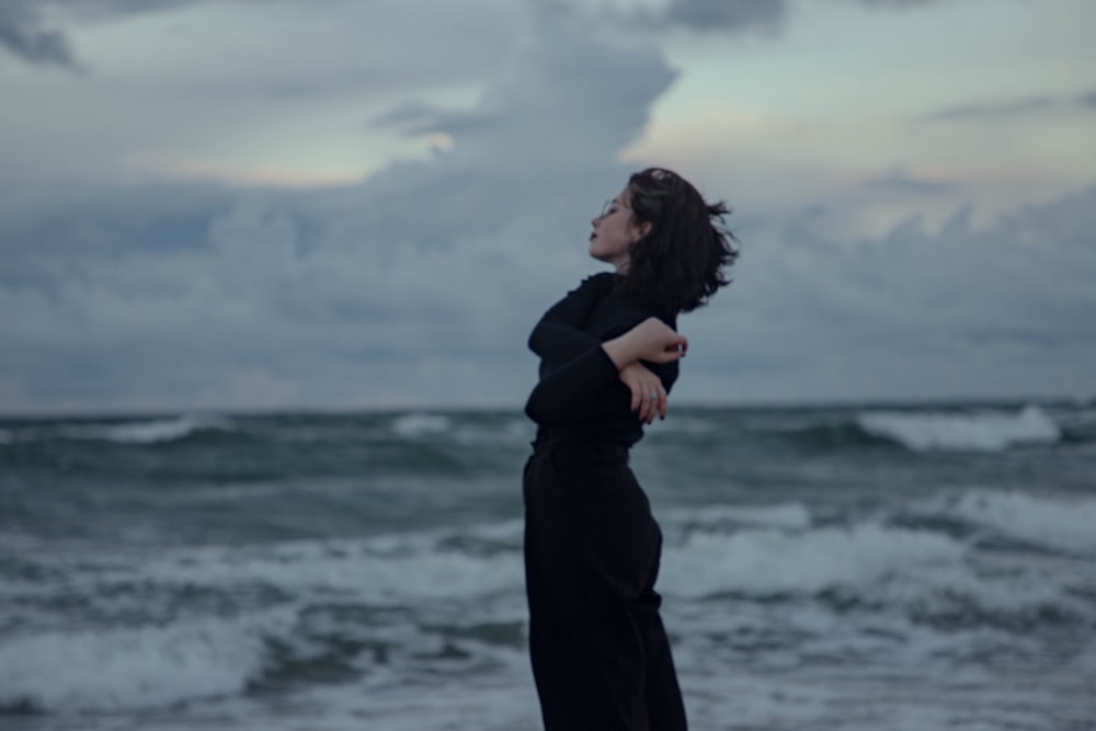 a woman standing on top of a beach next to the ocean