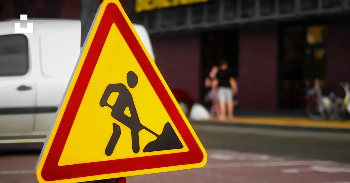 A yellow and red street sign sitting on the side of a road photo – Free ...