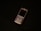 A classic mobile phone with a numeric keypad and small screen rests on a dark surface. The phone has a metallic finish with a black display and visible branding near the earpiece.