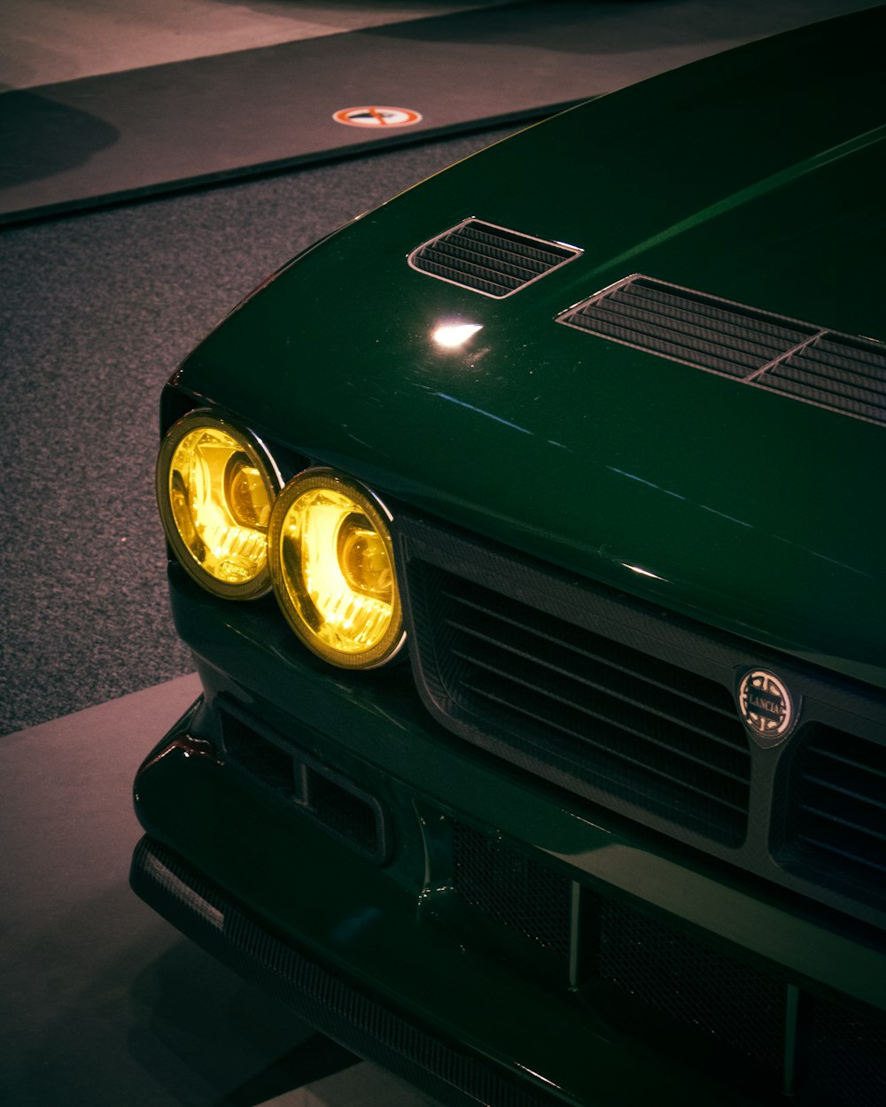 a close up of a green car with its lights on